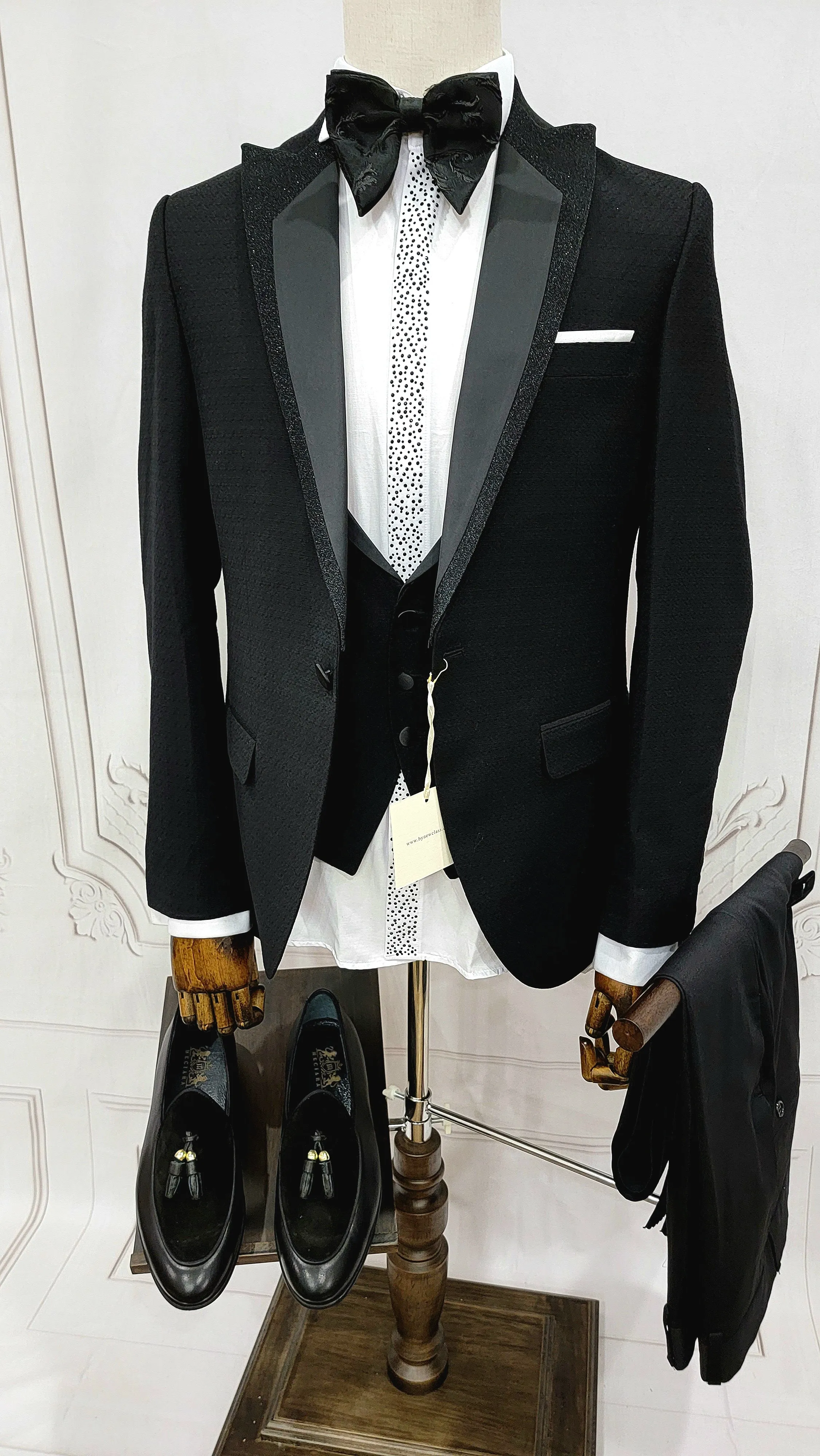 Single Button Three Pieces Tuxedo Suit with Black satin Lapel, matching bow tie and black dress pants.