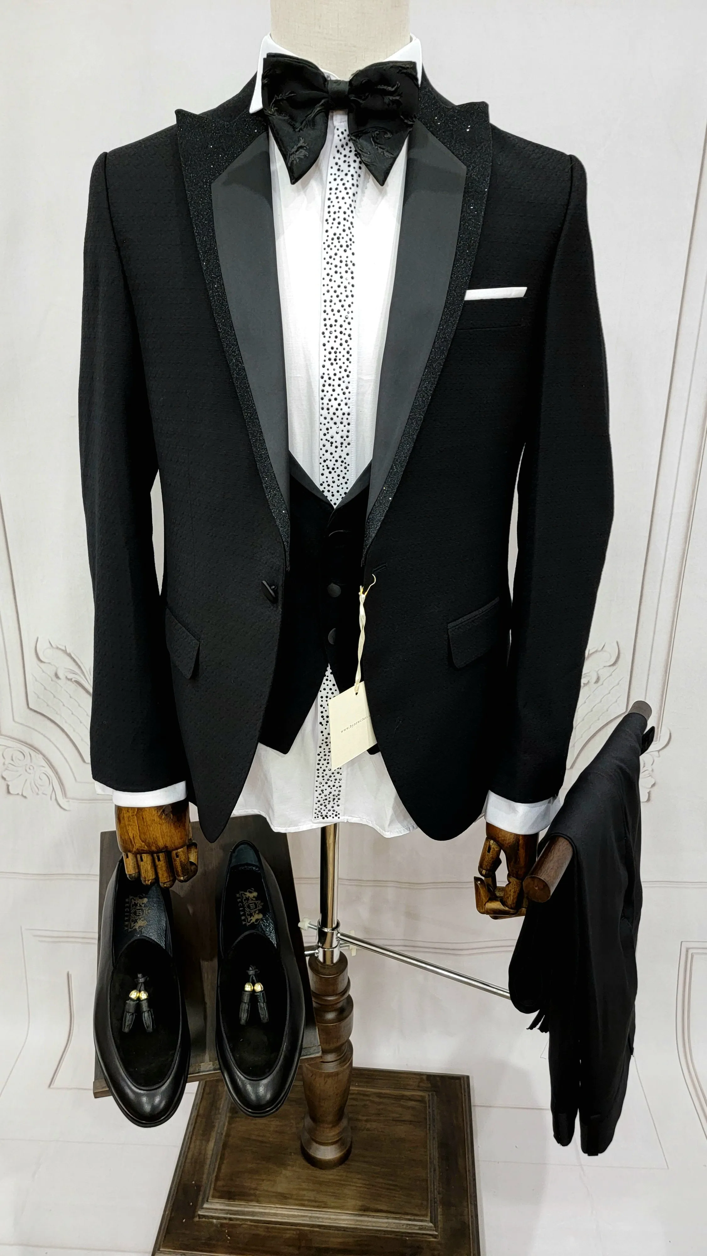 Single Button Three Pieces Tuxedo Suit with Black satin Lapel, matching bow tie and black dress pants.